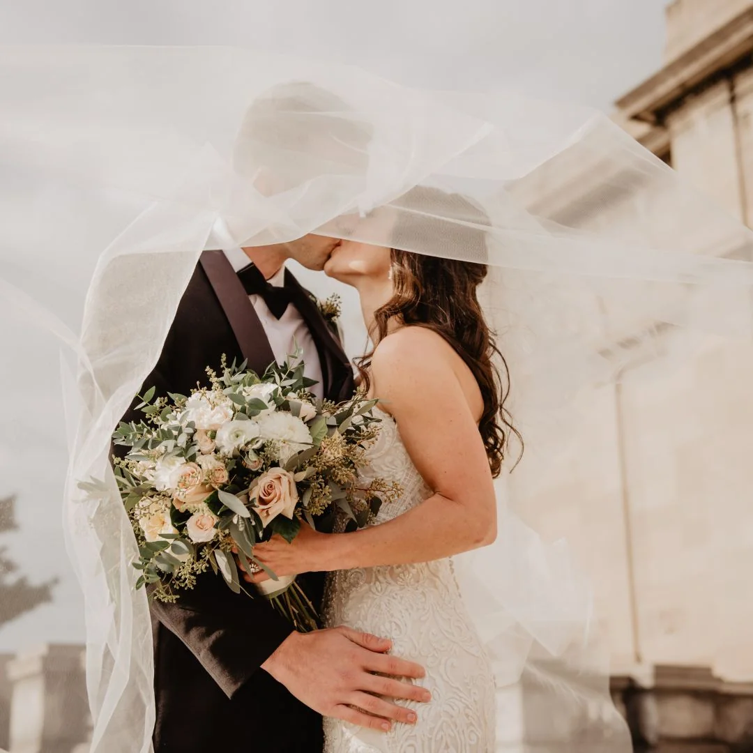 Bride and groom under a flowing wedding veil